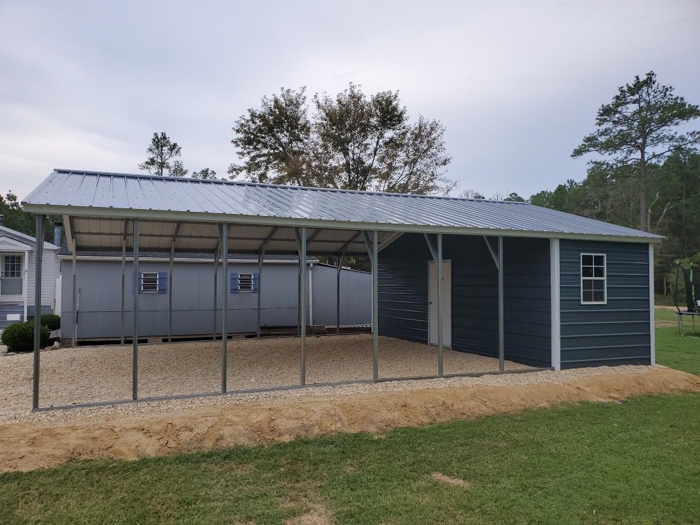 A combination carport and shed built with navy metal panels and a white-trimmed window.