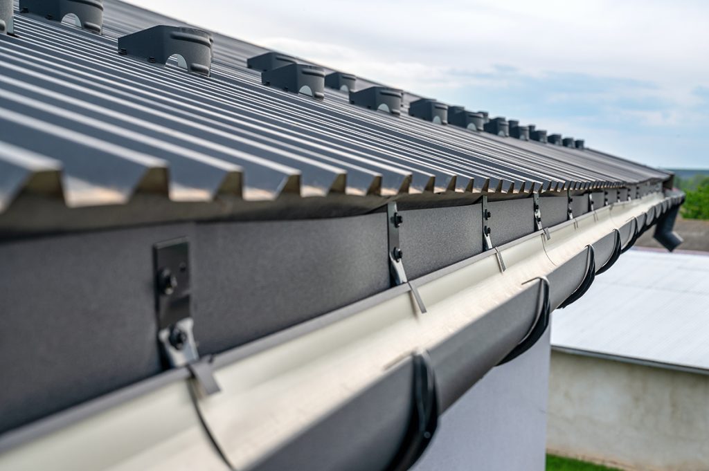 A close-up view of a black metal roof with matching gutter and drip-edge