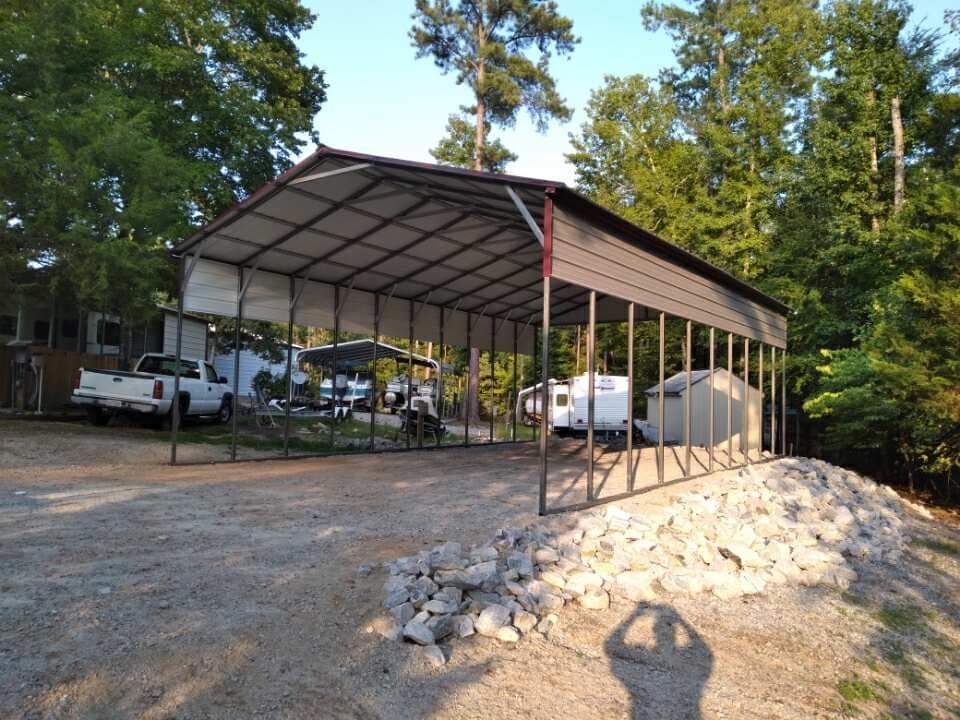 An unwalled carport with tan siding below the red roof.