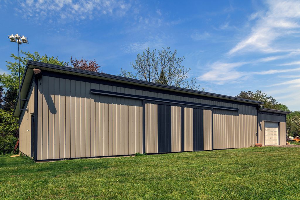 a tan building with dark brown trim and large sliding barn doors