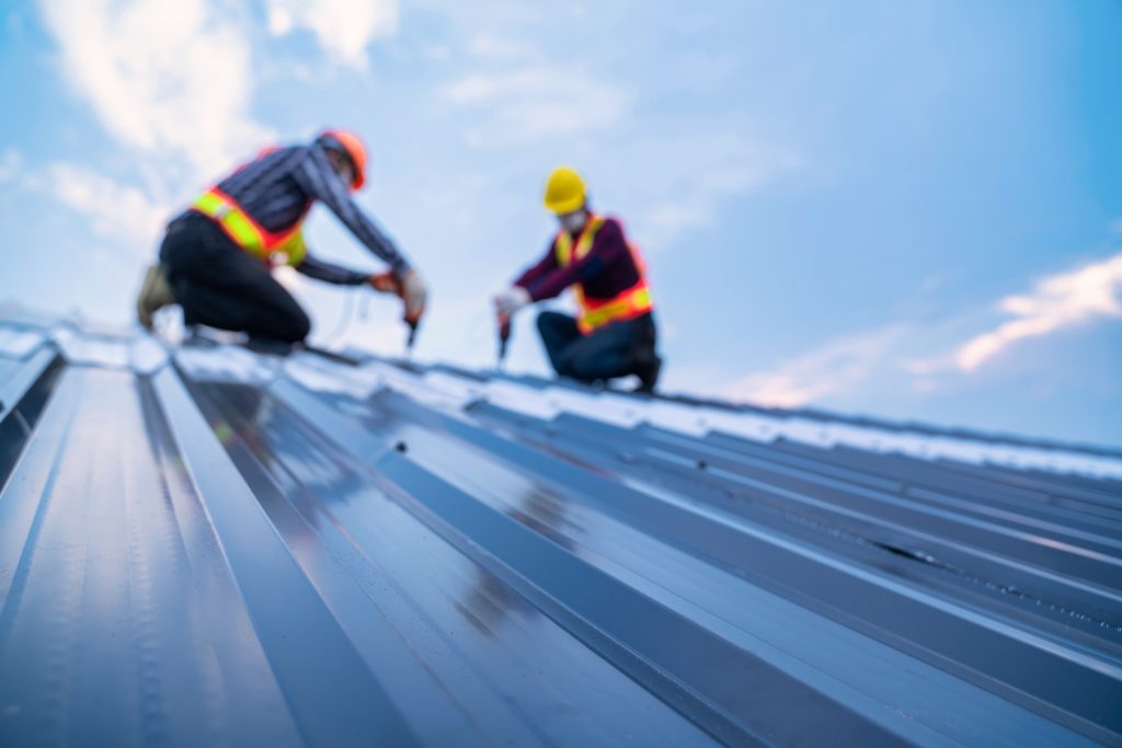 A view from below of metal building professionals on a metal roof